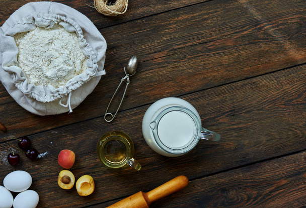On the table are the products for baking flour, eggs, milk and fresh fruit. Assistant cook spread ingredients for baking - Foto, Imagem
