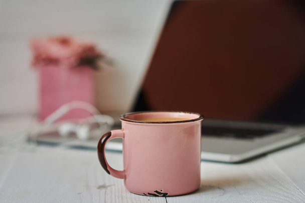 Stylish office desk workspace with laptop, notebook, pen, mug hot coffe with marshmallows and pink flowers on white vintage background. Lifestyle concept. Home office workspace. Women's desk. - Photo, image