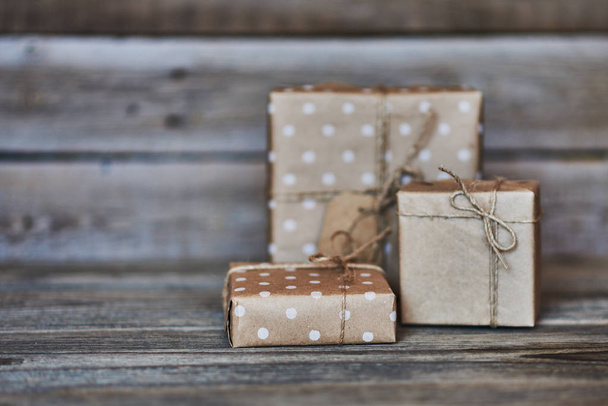 Handmade gift boxes wrapped with eco friendly craft paper and tied with twine on wooden vintage background. Background for your design. Holiday packing concept. Copy space for text. - Zdjęcie, obraz