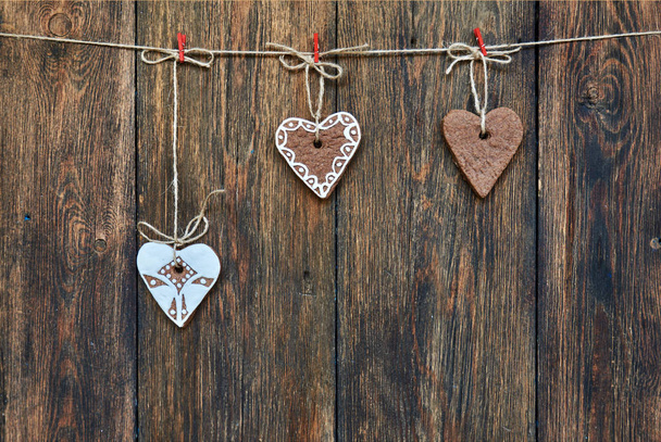 Gingerbread in the shape of a heart hanging on rope in front of dark  wooden background. - Фото, изображение