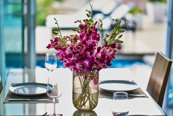 Kimppu violetti orkideat lasi maljakko ikkunan lähellä, vaakasuora kuva. Valikoiva painopiste
. - Valokuva, kuva