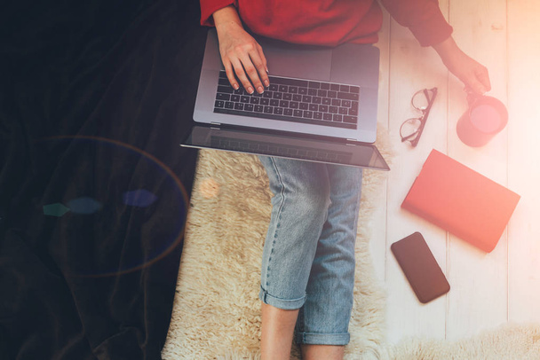 Young woman holding laptop computer on her lap while sitting at home. Woman using laptop for browsing internet store. Online shopping concept. Young woman sitting on carpet at home. - Foto, imagen