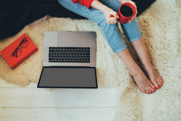 Intelligent woman sitting open notebook with copy space screen for your text message. Young woman looking at laptop. Top view of laptop in girls hands sitting on a wooden floor with coffee. - Foto, immagini