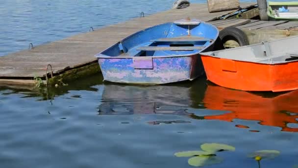 Een paar oude shabby en versleten boten verschillende kleuren op de pier van dok - Video
