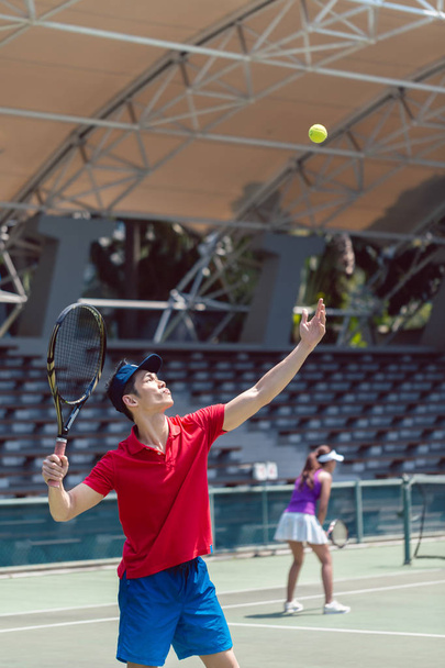 Asian tennis player ready to serve at the beginning of a doubles match - Foto, immagini