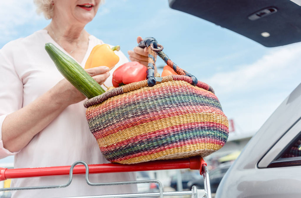 Iloinen vanhempi nainen, jolla on kori täynnä tuoreita vihanneksia
  - Valokuva, kuva