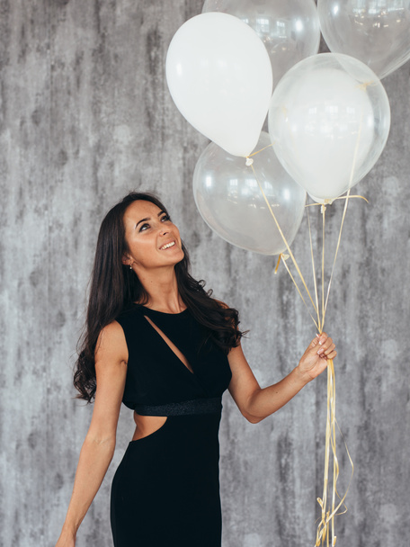 Cheerful young woman with balloons standing and smiling - Foto, imagen