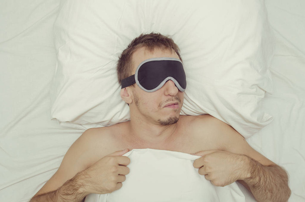 Відпочиваючи в маски для сну людини. Стерні на його обличчі. Втомився людина - Фото, зображення