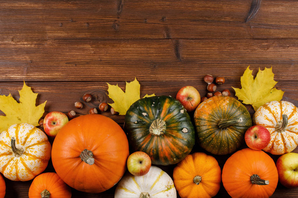 Autumn harvest still life with pumpkins, apples, hazelnut and maple leaves on wooden background - Zdjęcie, obraz