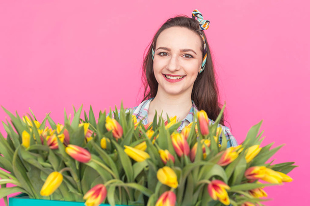 Közelről rózsaszín háttér tulipán csokorral barna fiatal nő portréja - Fotó, kép