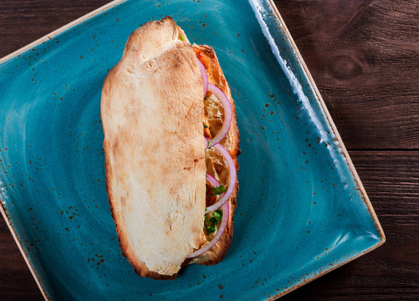 Pollo grigliato in sandwich da pane di pita fresco con cipolla e verdure su sfondo di legno scuro. Shashlik o Shish kebab. Pranzo sano
 - Foto, immagini