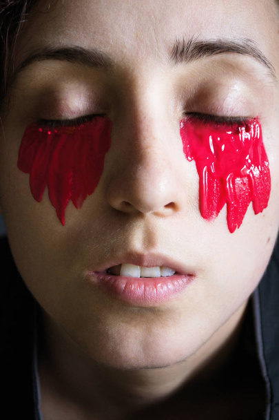 Gözlerinin altında kırmızı boya ile siyah giysili kapalı gözlü bir kız resmi moda yakın çekim portresi - Fotoğraf, Görsel