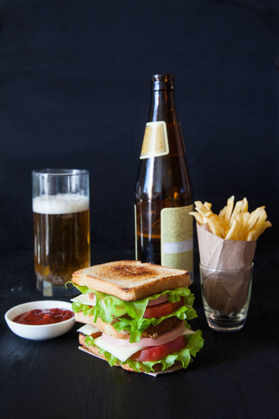 sandwich with beer and french fries on a black background - Foto, immagini