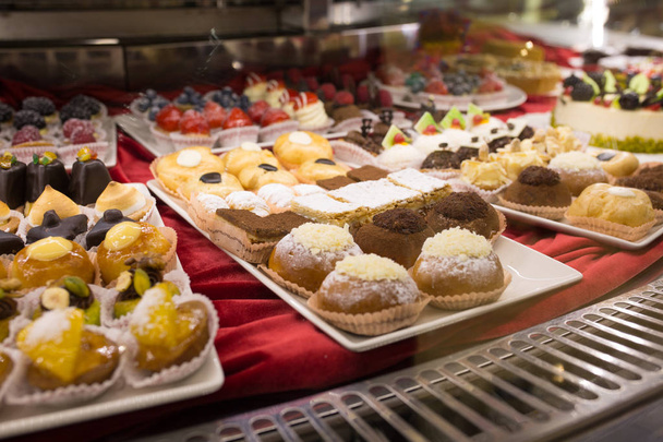 Diferentes coloridos sabrosos pasteles hermosos en un escaparate en caf
 - Foto, Imagen