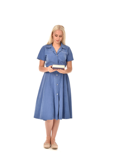 po celé délce portrét blond dívka, která nosí modré šaty. stojící pozice drží knihu. izolované na bílém studio pozadí. - Fotografie, Obrázek