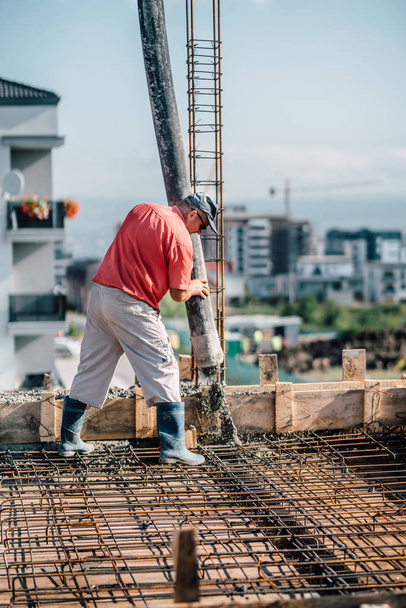промисловий працівник експлуатує цементний насос, деталі промислового обладнання та будівельний майданчик
 - Фото, зображення