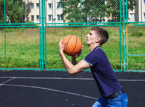 mladý muž hrát basketbal venkovní na slunečný letní den closeup - Fotografie, Obrázek
