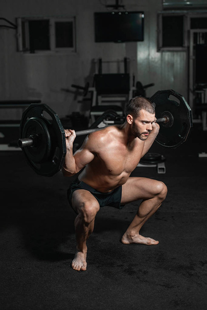 Handsome weightlifter lifting barbells with Squats. Male training with barbell, pumping legs - Foto, Bild