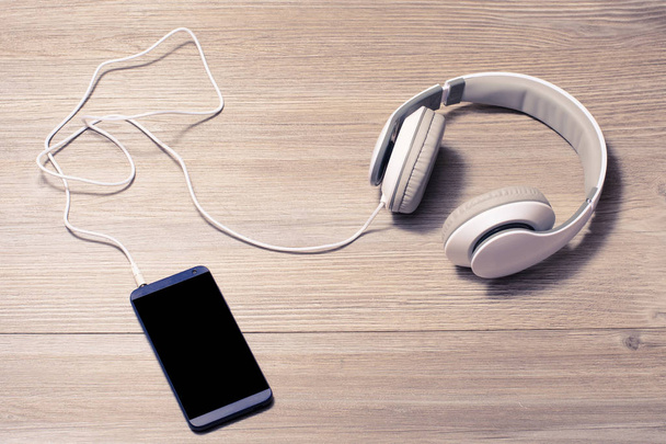Bílá sluchátka a mobilní telefon na stůl  - Fotografie, Obrázek