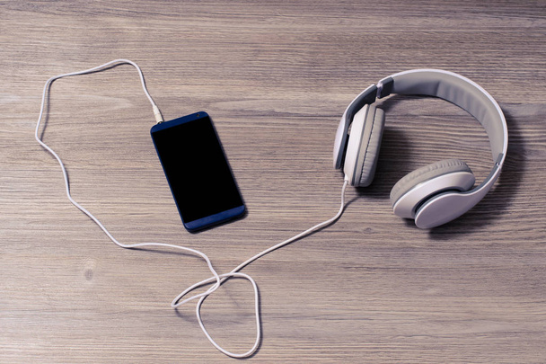 Bílá sluchátka a mobilní telefon na stůl - Fotografie, Obrázek