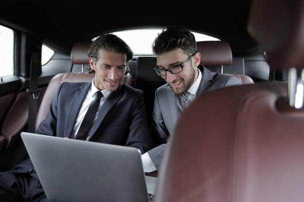 two businessman talking while sitting in the car - Foto, Bild