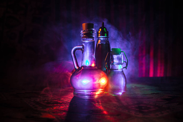 Işık ile karanlık sisli zemin üzerine antika ve vintage cam şişeler. Zehir ya da sihirli sıvı kavramı. - Fotoğraf, Görsel