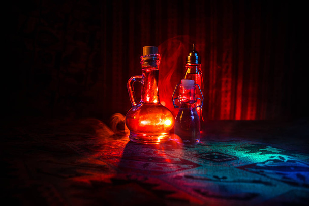 Garrafas de vidro antigas e vintage no fundo nebuloso escuro com luz. Conceito de veneno ou líquido mágico
. - Foto, Imagem