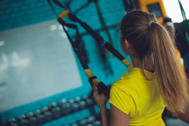Training with TRX. Young woman in the gym making fitness training - Photo, image