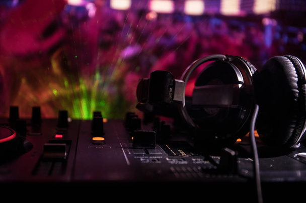 In selective focus of Pro dj controller.The DJ console deejay mixing desk at music party in nightclub with colored disco lights. Close up view - Photo, Image