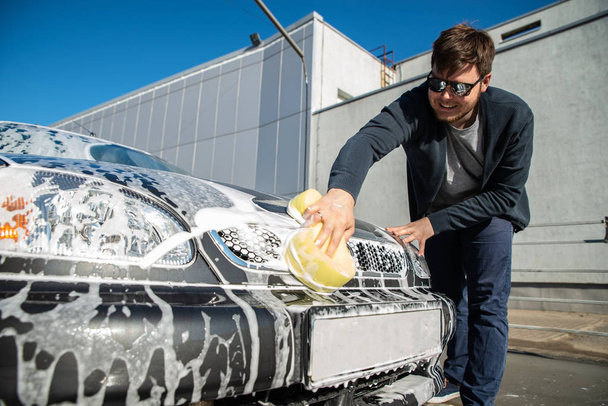 young man in sunglasses washing car at self service carwash - Photo, Image