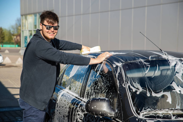 joven hombre en gafas de sol lavado de coches en auto servicio de lavado de coches
 - Foto, imagen
