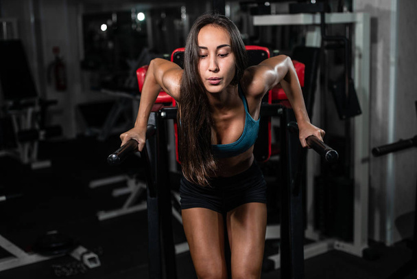 Fitness woman doing push-ups on uneven bars in crossfit gym. Workout lifestyle concept - Foto, Imagen