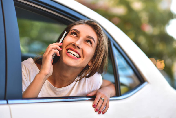 Bella donna con il telefono sorridente mentre seduto sul sedile posteriore in auto
. - Foto, immagini