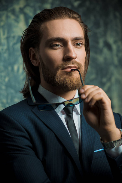 Fashion shot. Handsome young man posing in elegant suit over dark background. Men's beauty, fashion. - Foto, imagen