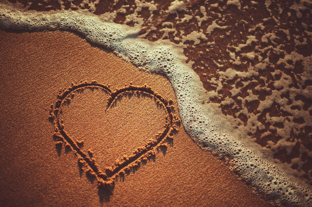 Las olas del mar y el corazón dibujando en la playa de arena cerca del océano. Concepto de amor verano
. - Foto, imagen
