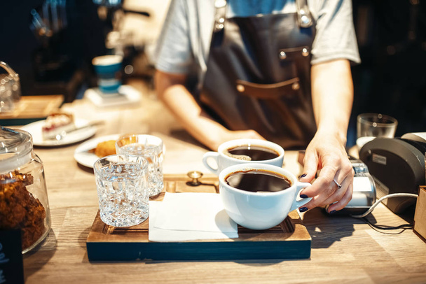 Αρσενικό barista με φλιτζάνια φρέσκο ζεστό μαύρο καφέ, καφέ μετρητή σε φόντο. Εσπρέσσο επαγγελματική προετοιμασία από καφετέρια, επάγγελμα μπάρμαν μπάρμαν - Φωτογραφία, εικόνα