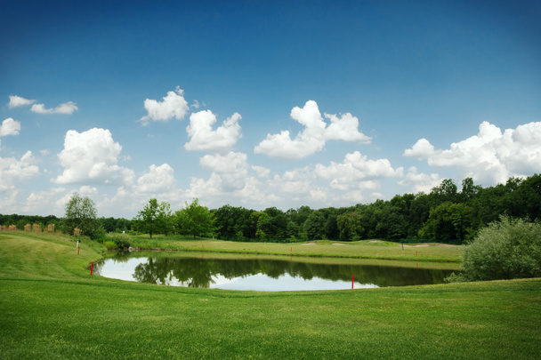 Озеро, подстриженная лужайка и песчаные бункеры для гольфа на поле для гольфа, никто. Луг в спортивном клубе, ландшафт игровой площадки
 - Фото, изображение