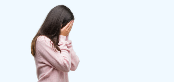 Młody piękny hiszpanin kobieta swetrze z smutny wyrażenie obejmujące twarz rękami podczas płaczu. Koncepcja depresji. - Zdjęcie, obraz