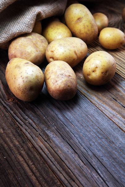 Perunaruokaa. Tuoreet luonnonmukaiset perunat vanhalla vintage-taustalla
 - Valokuva, kuva
