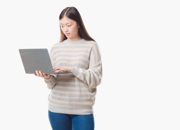 Giovane donna cinese su sfondo isolato utilizzando computer portatile con un'espressione fiduciosa sul viso intelligente pensando grave
 - Foto, immagini
