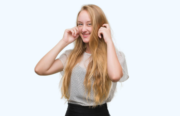 Mujer adolescente rubia con topos camisa que cubre las orejas con los dedos con expresión molesta por el ruido de la música alta. Concepto sordo
. - Foto, imagen