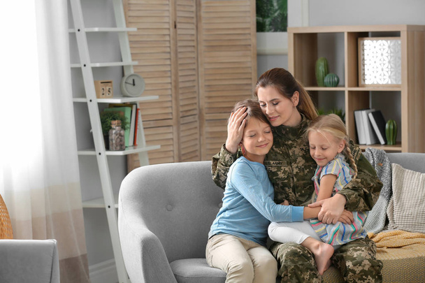 Woman in military uniform with her children on sofa at home - Foto, Imagen