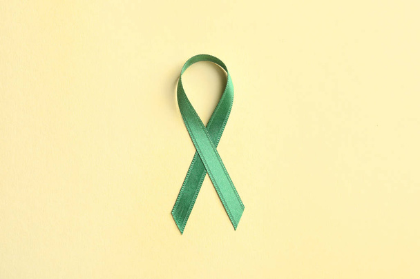 Green ribbon on color background, top view. Cancer awareness - Fotografie, Obrázek
