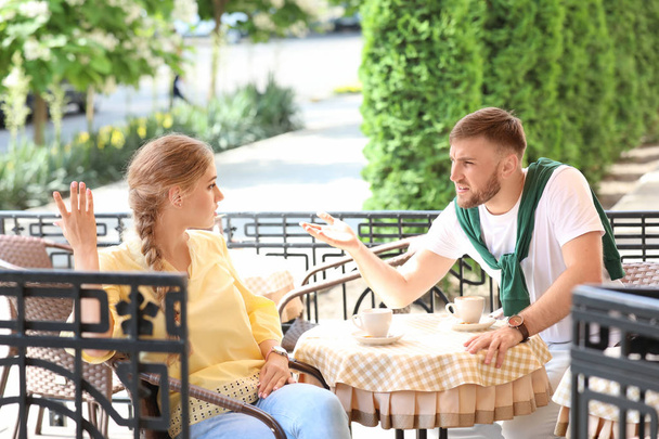 Young couple arguing while sitting in cafe, outdoors. Problems in relationship - Foto, immagini