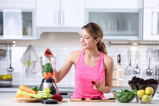 Young woman preparing tasty healthy smoothie at table in kitchen - Foto, afbeelding