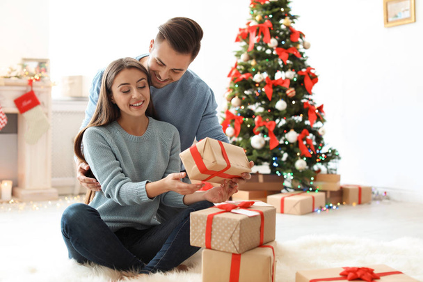 Young man giving Christmas gift to his girlfriend at home - Foto, Imagem