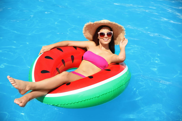 Beautiful young woman with inflatable ring in swimming pool - Fotografie, Obrázek