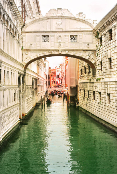 Venice, Italy, Jun 8, 2018: View of bridge of sighs with gondoliers carrying tourists in their gondolas in Venice, italy at sunset - Photo, Image