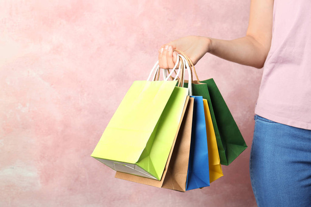 Woman holding paper shopping bags on color background - Fotoğraf, Görsel