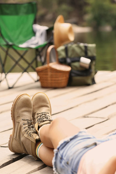 Woman resting near camping equipment on wooden pier, focus on legs - Fotografie, Obrázek